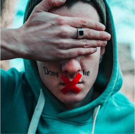 Mensch, der sich die Augen zuhält. Auf seinem Mund klebt ein rotes Kreuz